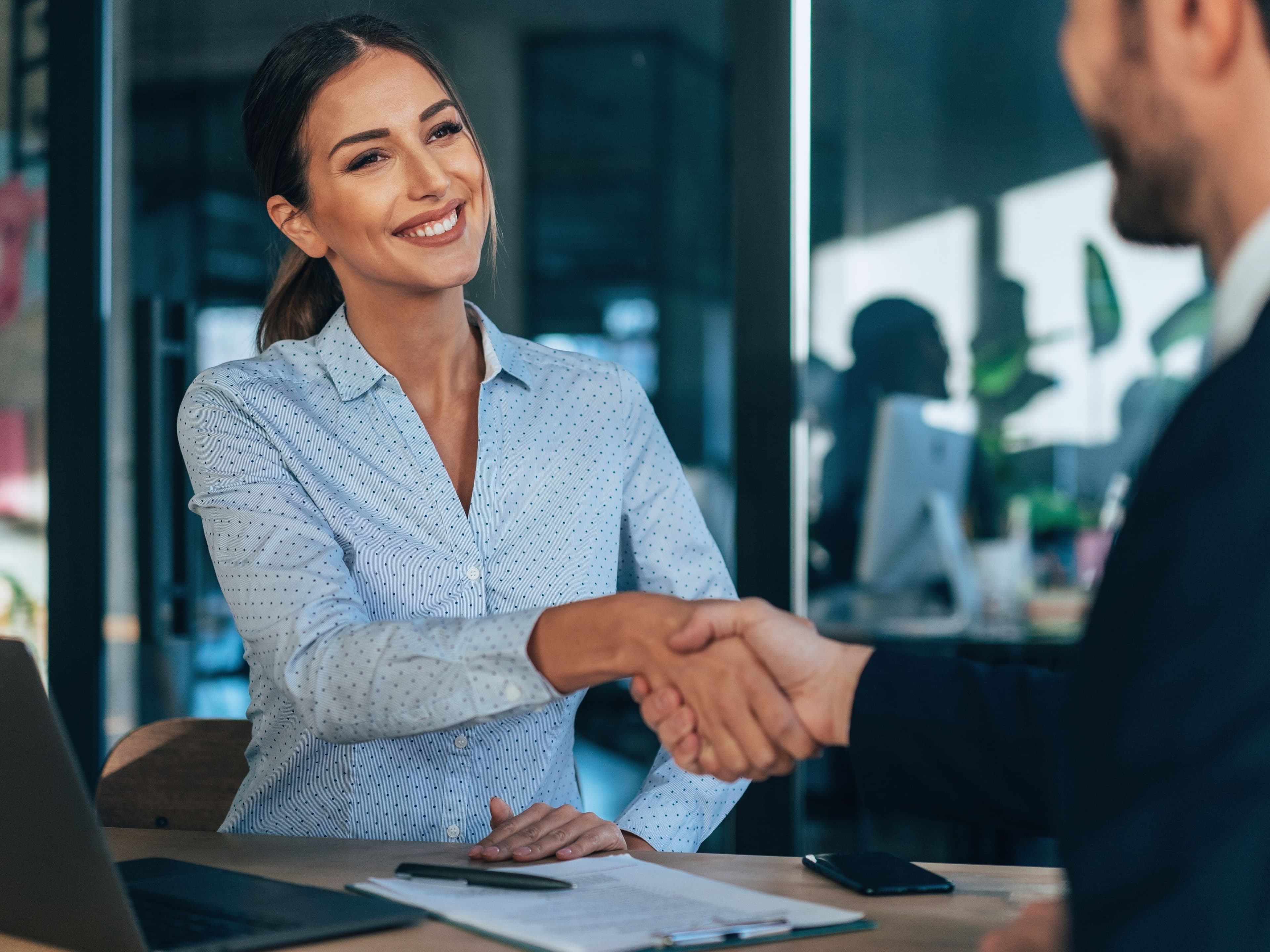 Ejecutiva saludando a un cliente en una reunión